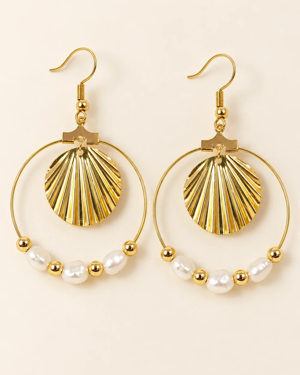 Agnès — Crochets dorés, grandes créoles avec pendentif coquillage strié au centre; perles blanches irrégulières et petites perles dorées sur le bas de chaque cercle.
