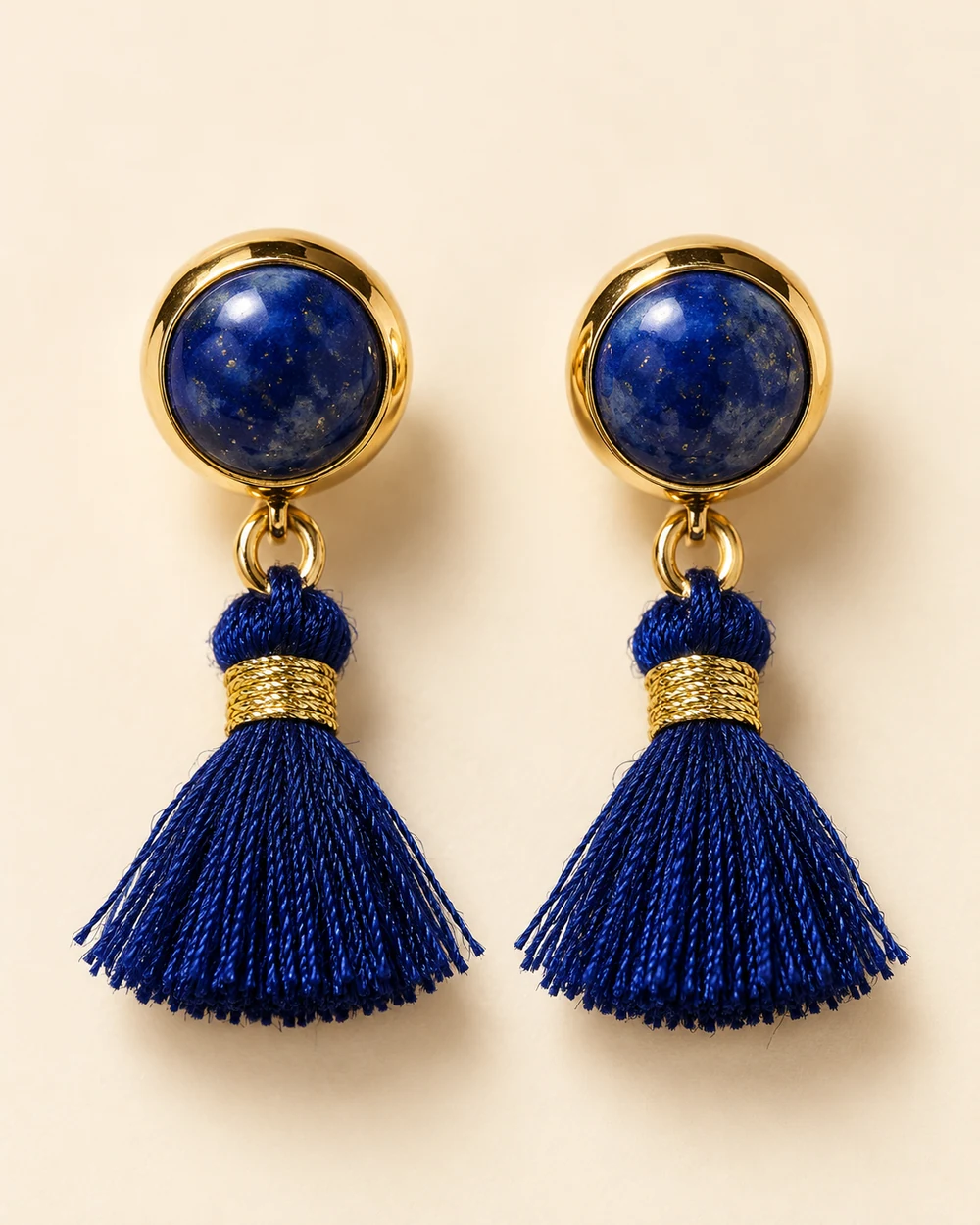 Badette — Puces à cabochons ronds bleu foncé sur supports dorés; petits pompons bleu foncé à ligature dorée suspendus par anneau.