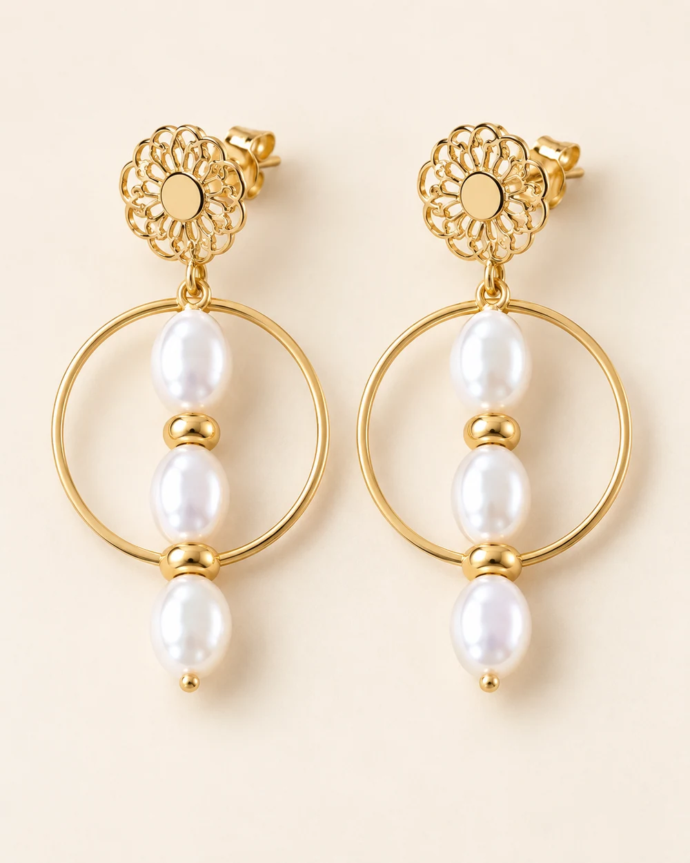 Bénédicte — Puces florales ajourées dorées, cercles fins et trois perles blanches ovales alignées par boucle, séparées par de petites rondelles dorées.