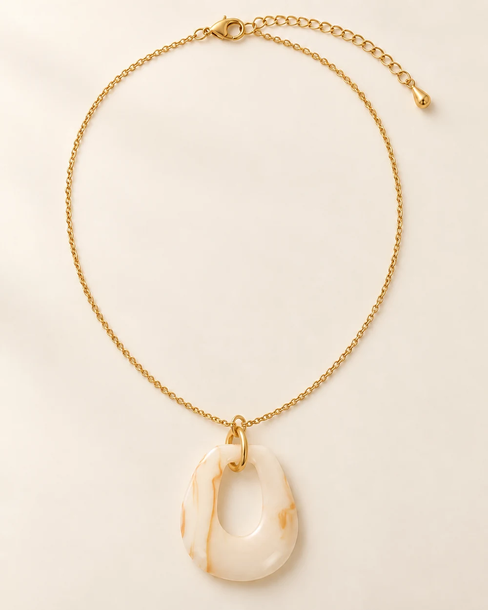 Calice — Goutte évidée beige, sur chaîne fine de 60 cm.