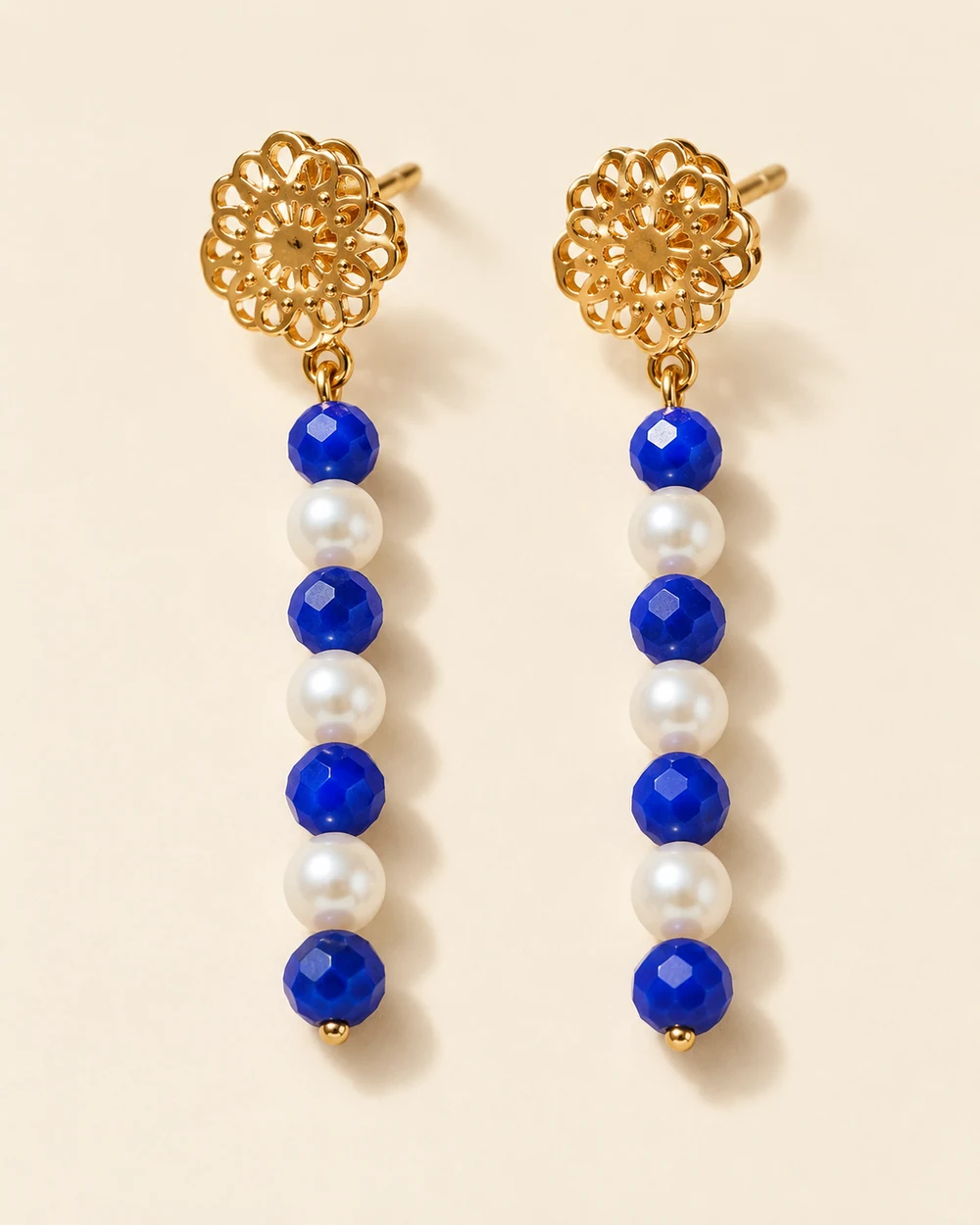 Morgan — Puces florales ajourées dorées; pendants linéaires alternant quatre petites perles bleues facettées et trois perles blanches par boucle.