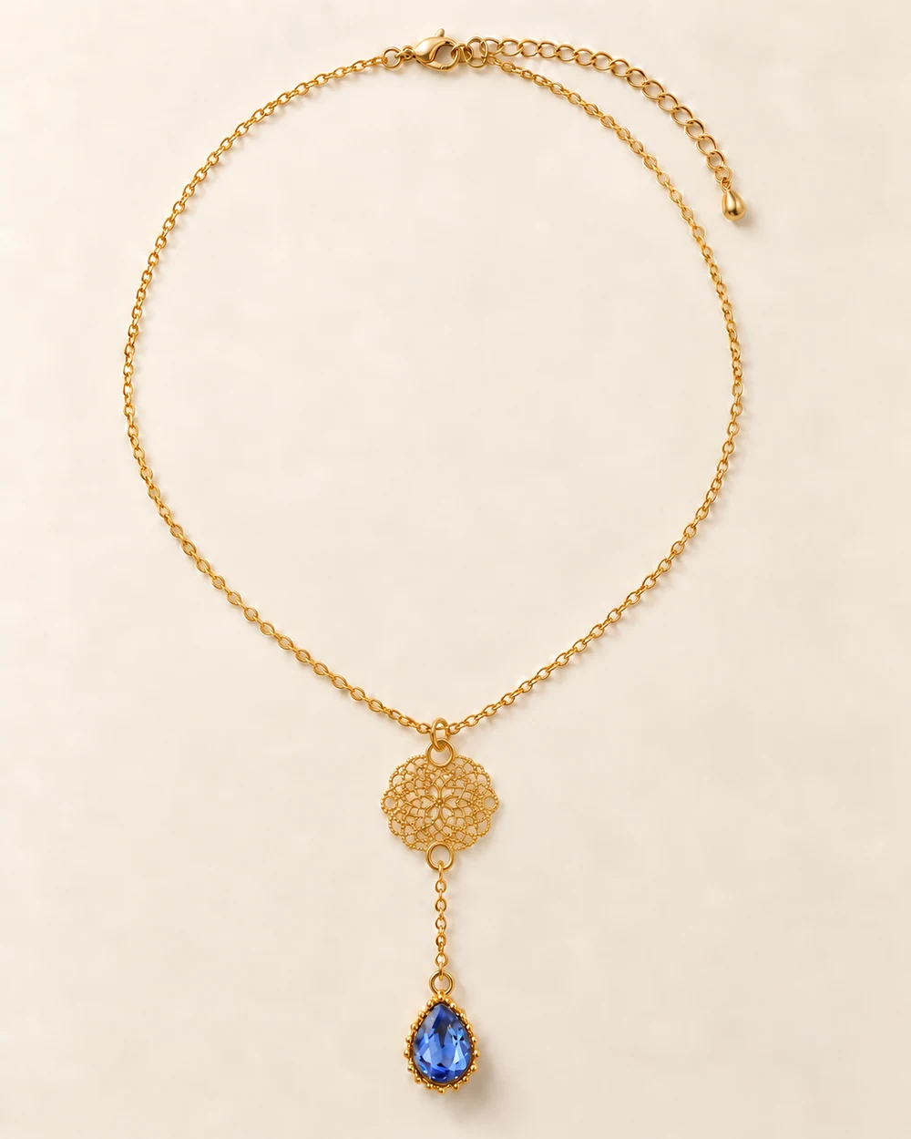 Rivage — Une ligne en Y : rosace dorée à deux trous, puis goutte de verre bleu clair montée au bout d’une descente de 8 cm.